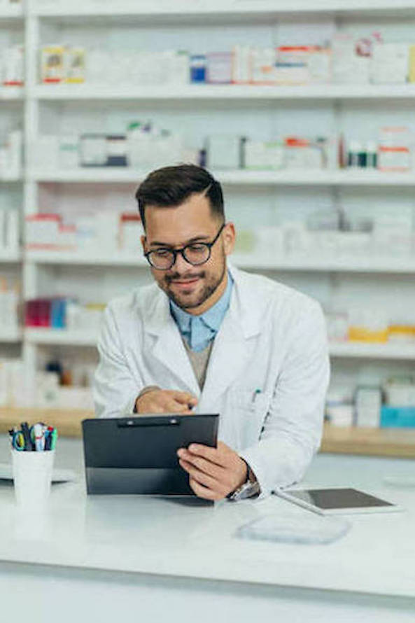 Portrait of a handsome pharmacist working in a pharmacy and using a computer